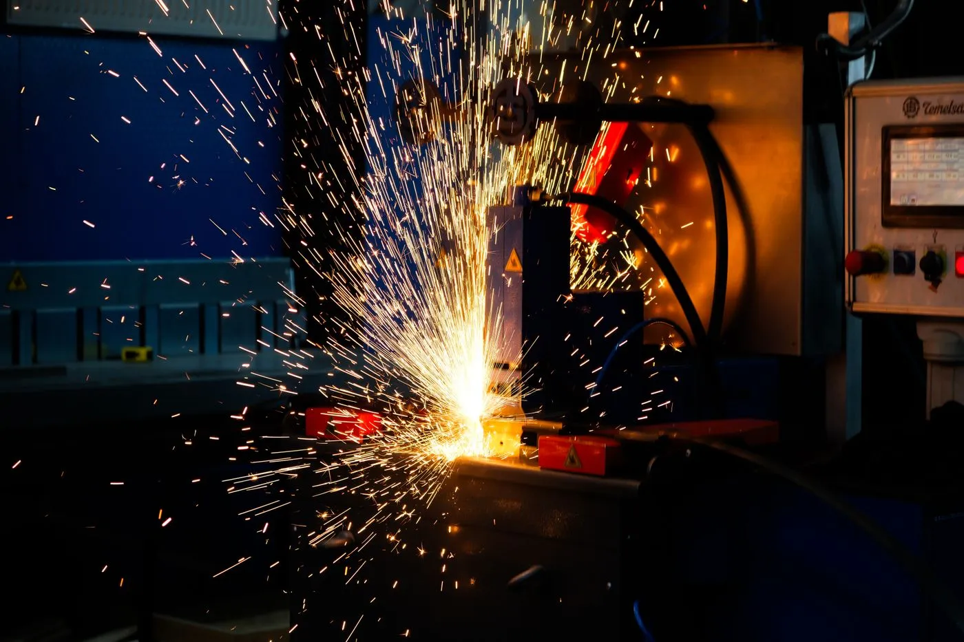 Sparks flying from a metal fabrication machine in a dark workshop
